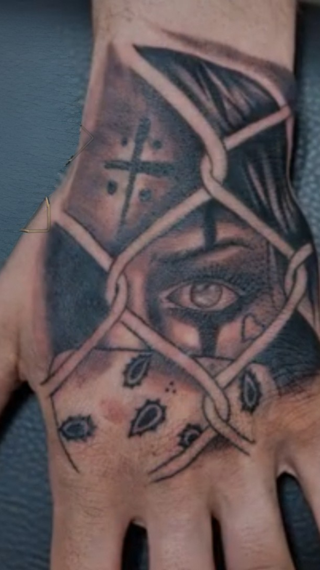 Black and grey hand tattoo with an eye and cross woven through a bandana pattern