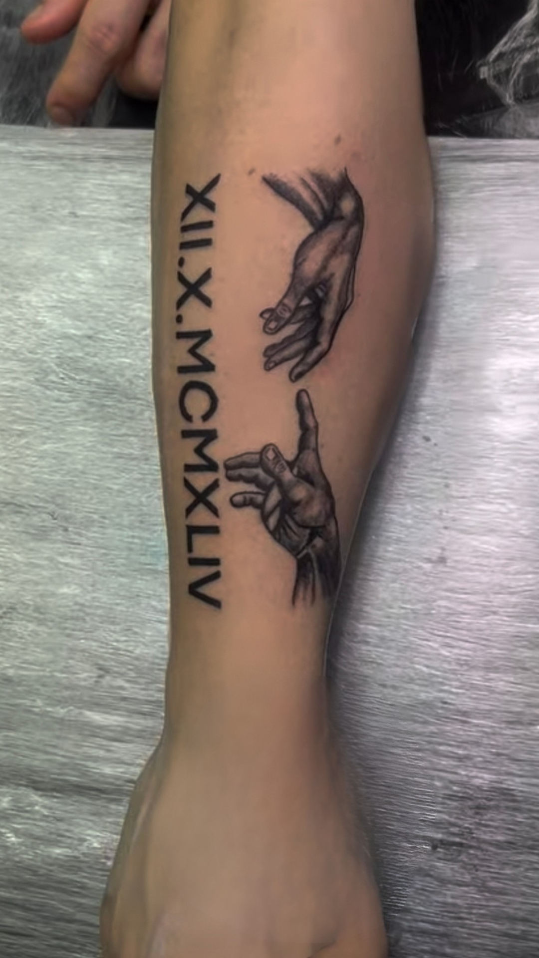 Black and grey Michelangelo-style hands with Roman numerals on calf
