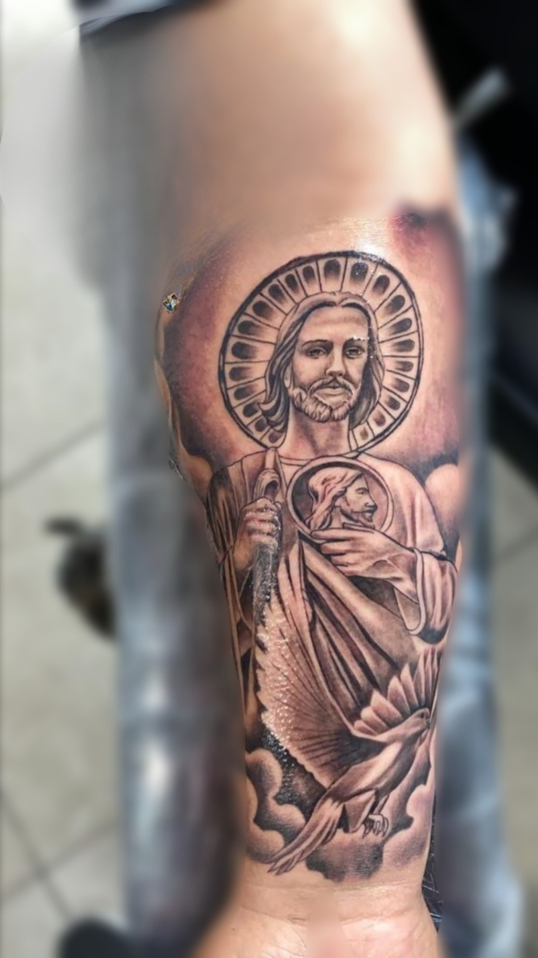 Black and grey realism tattoo of Jesus with halo on forearm