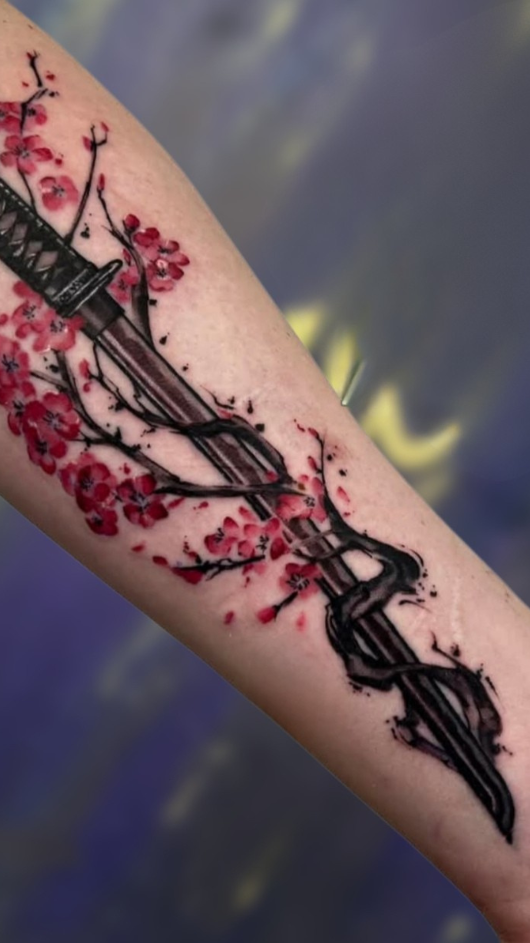 Katana with red cherry blossoms tattoo on forearm