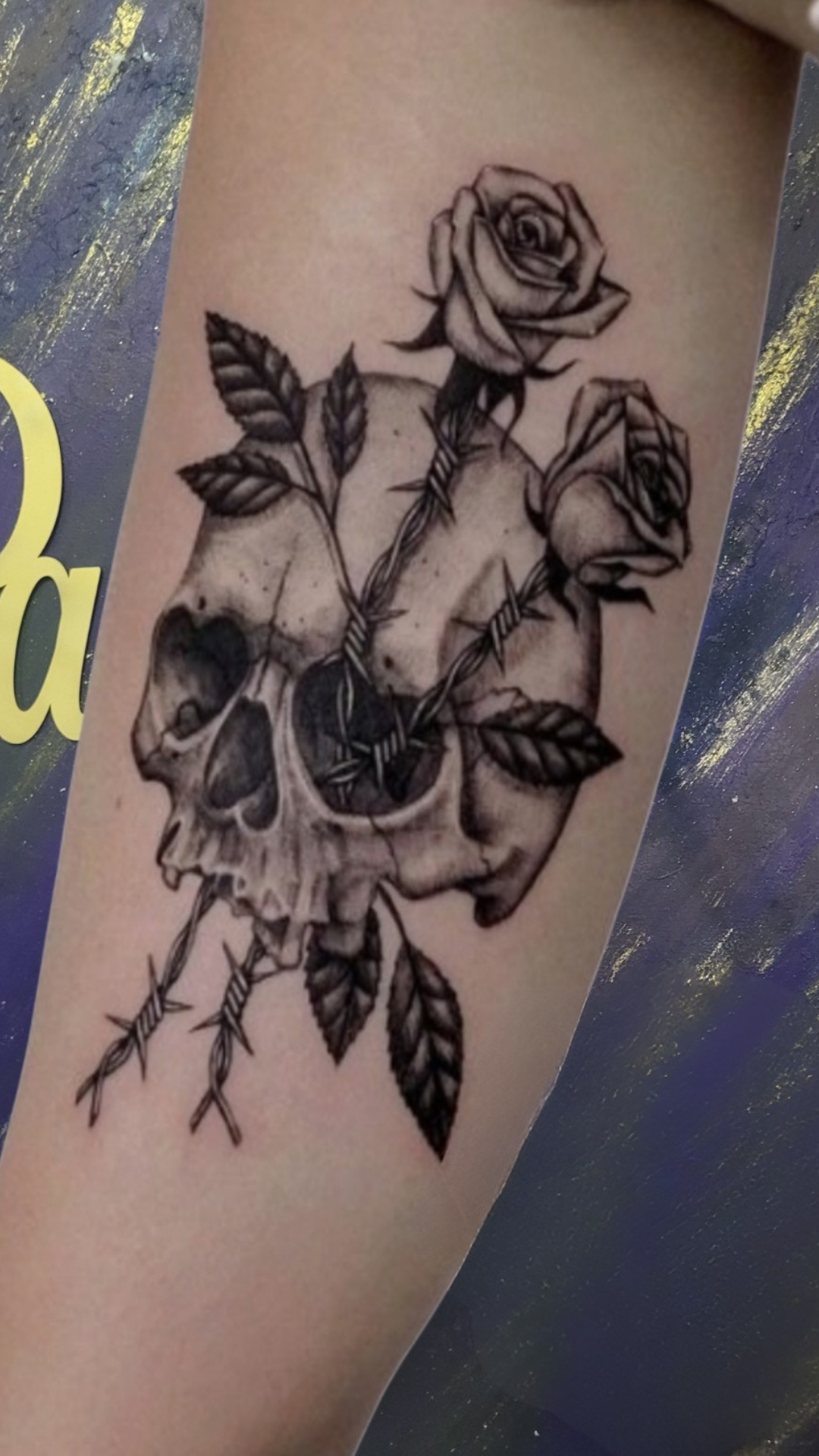 Black and grey skull with roses tattoo on forearm