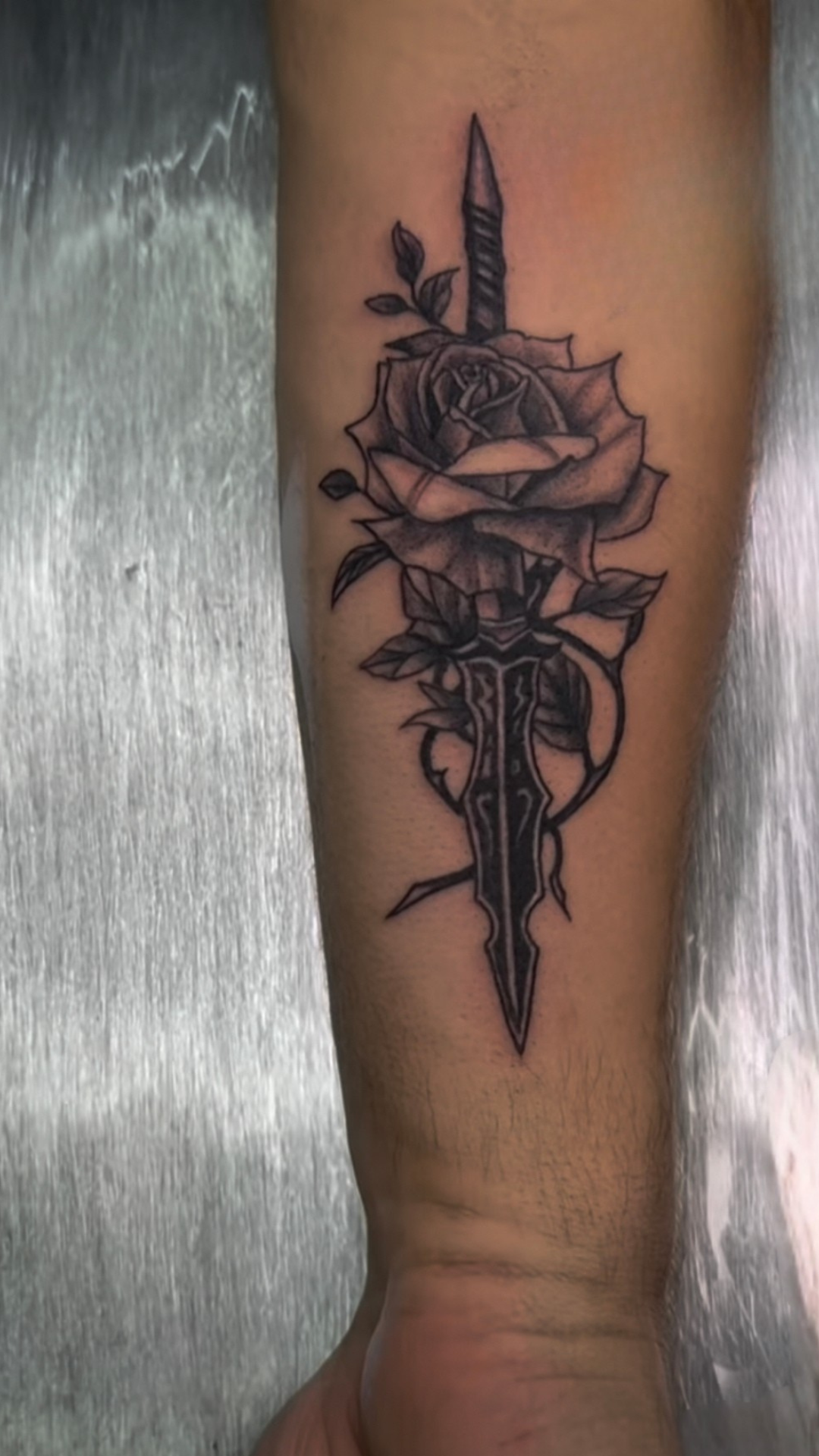 Neo-traditional dagger and rose tattoo on forearm