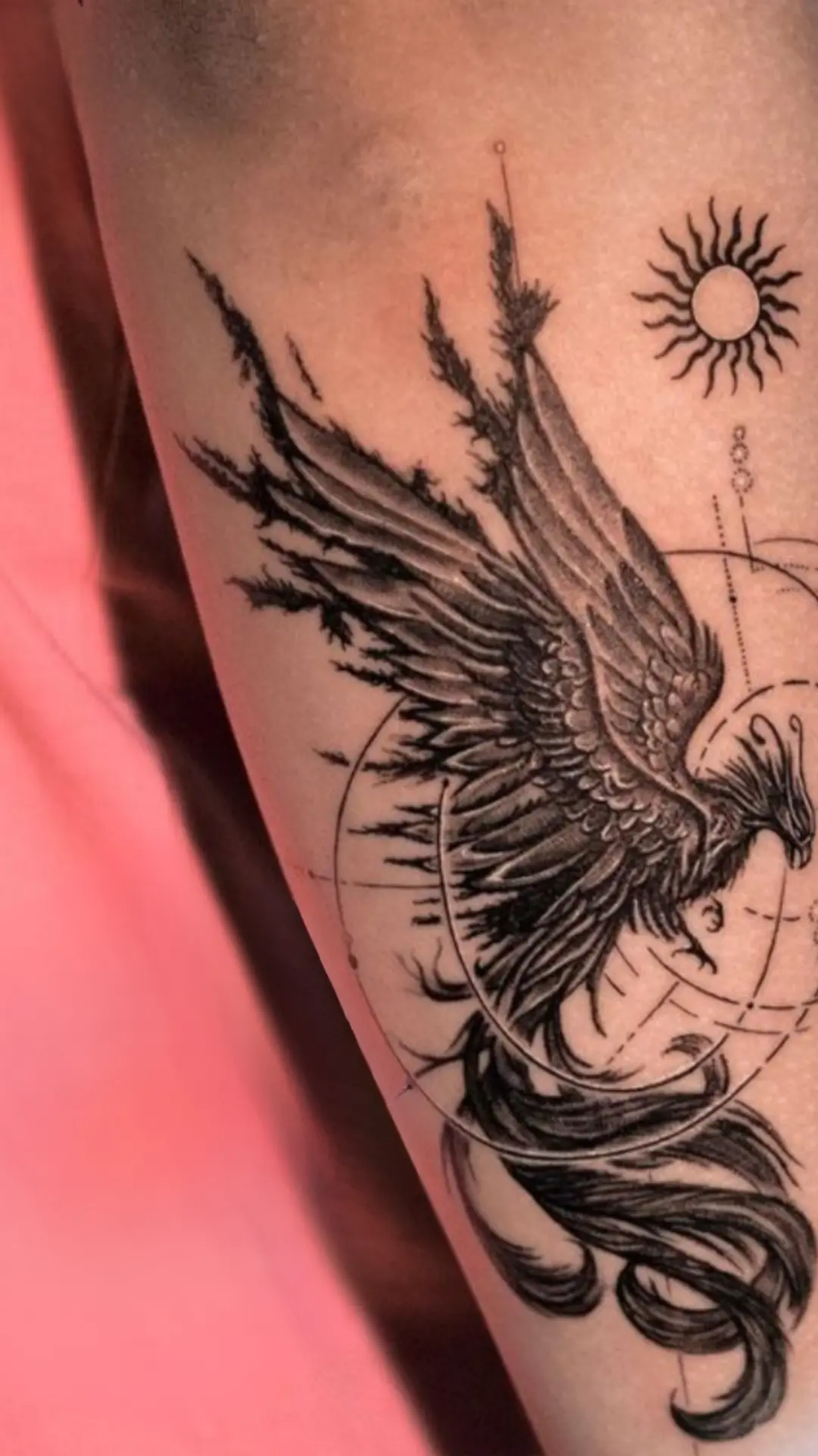 Fine-line phoenix with sun tattoo on forearm